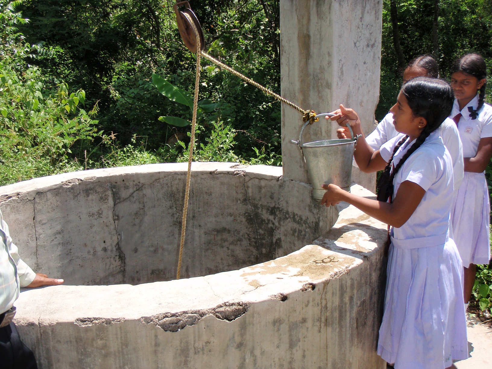 Een meisje haalt water uit een waterput in Sri Lanka.