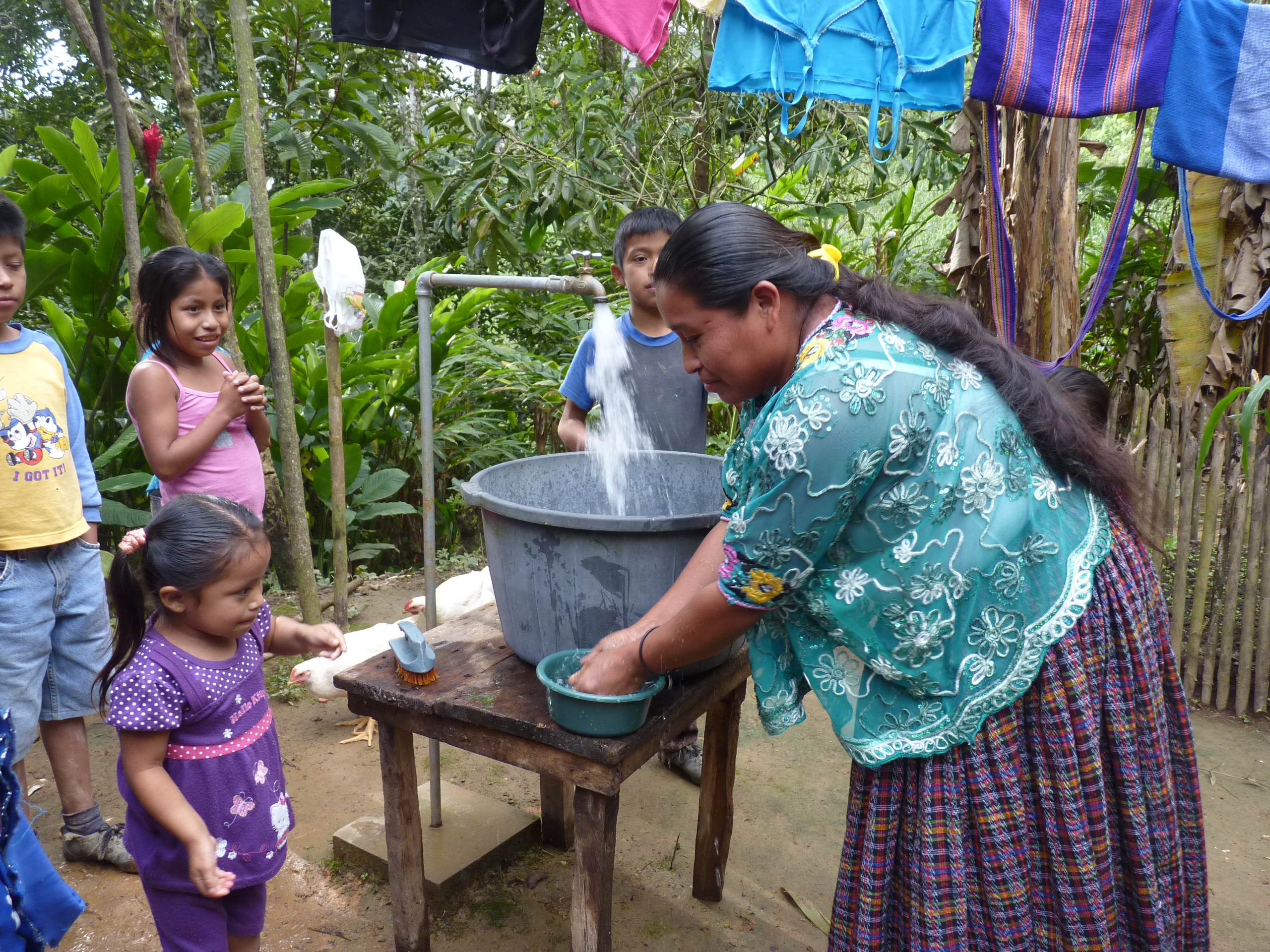 Een vrouw tapt schoon water in een ton in Guatemala