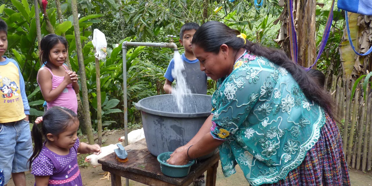 Een vrouw tapt schoon water in een ton in Guatemala