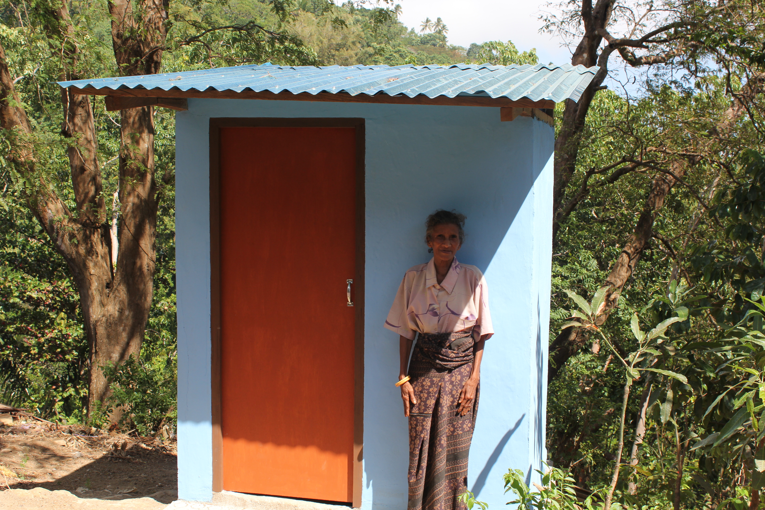 Een oudere vrouw poseert bij een nieuwe wc in Indonesië.