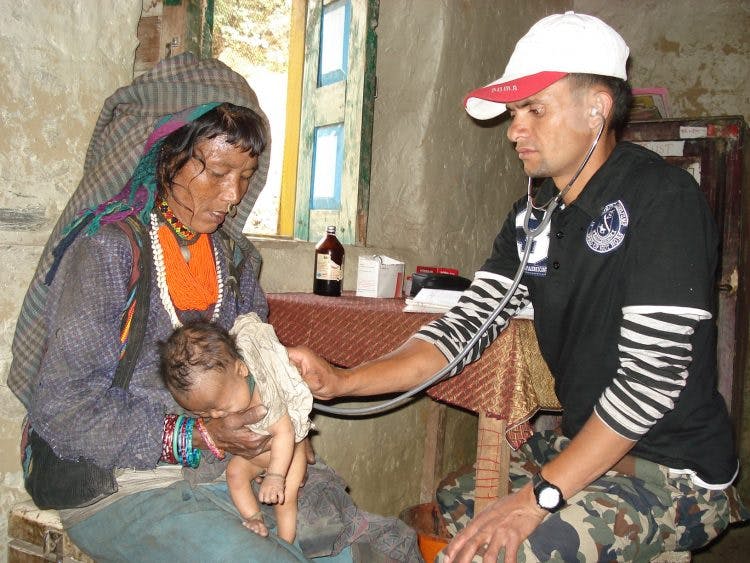 Een vrouw in Nepal laat haar kind onderzoeken door een arts.