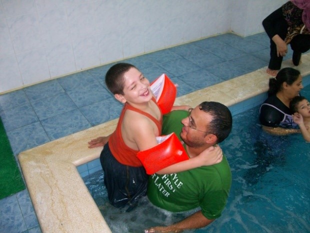 Een vader met zijn zoon in een zwembad voor Fysiotherapie in Libanon.