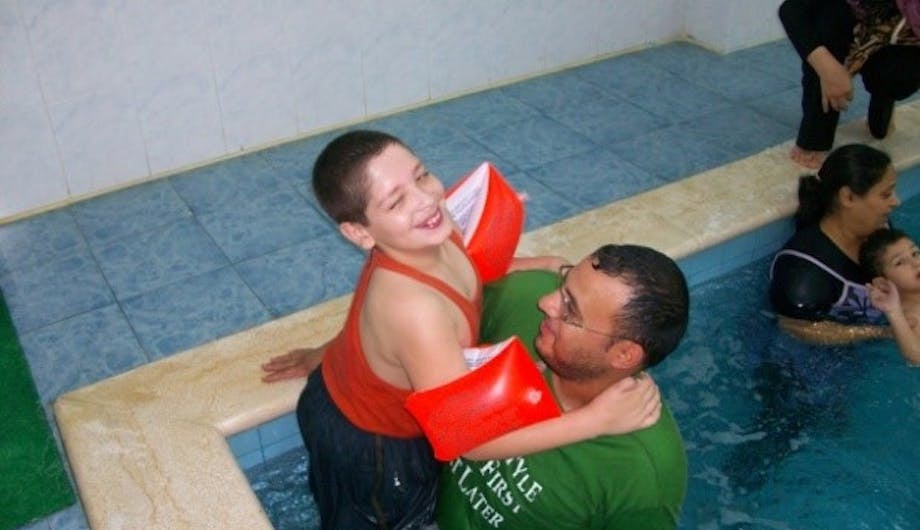 Een vader met zijn zoon in een zwembad voor Fysiotherapie in Libanon.
