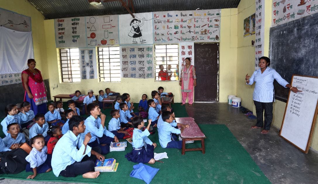 Kinderen zitten op de grond in een les op een dovenschool in Nepal.
