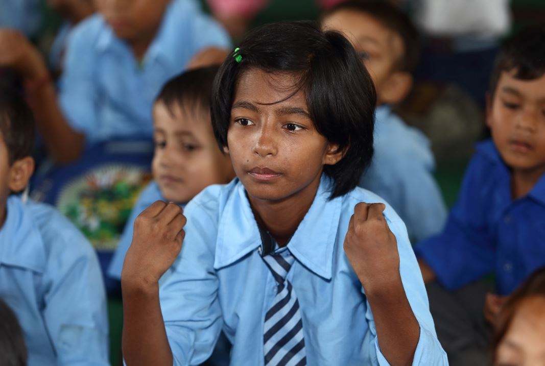 Een meisje oefent handgebaren tijdens een les in Nepal.