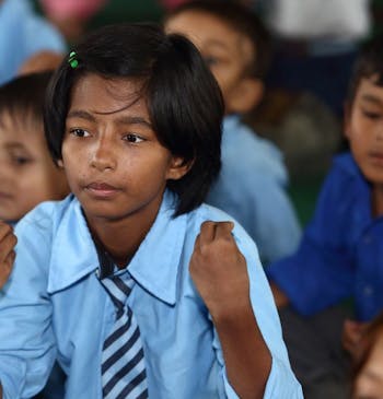 Een meisje oefent handgebaren tijdens een les in Nepal.