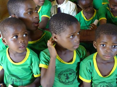 Drie kleine kinderen met groene shirtjes in Nigeria.
