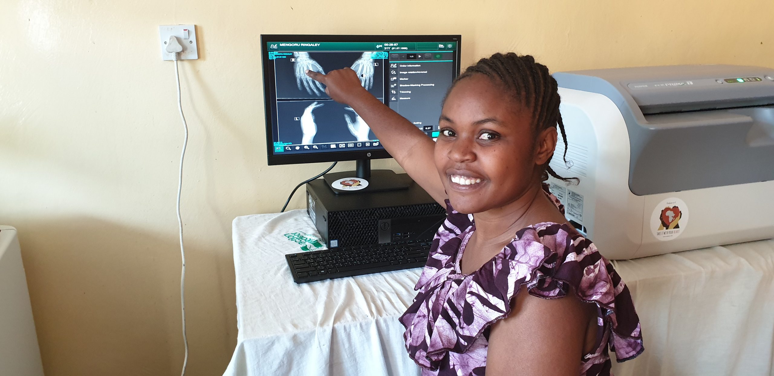 Een meisje wijst naar een computerscherm met daarop een rontgenfoto van handen.