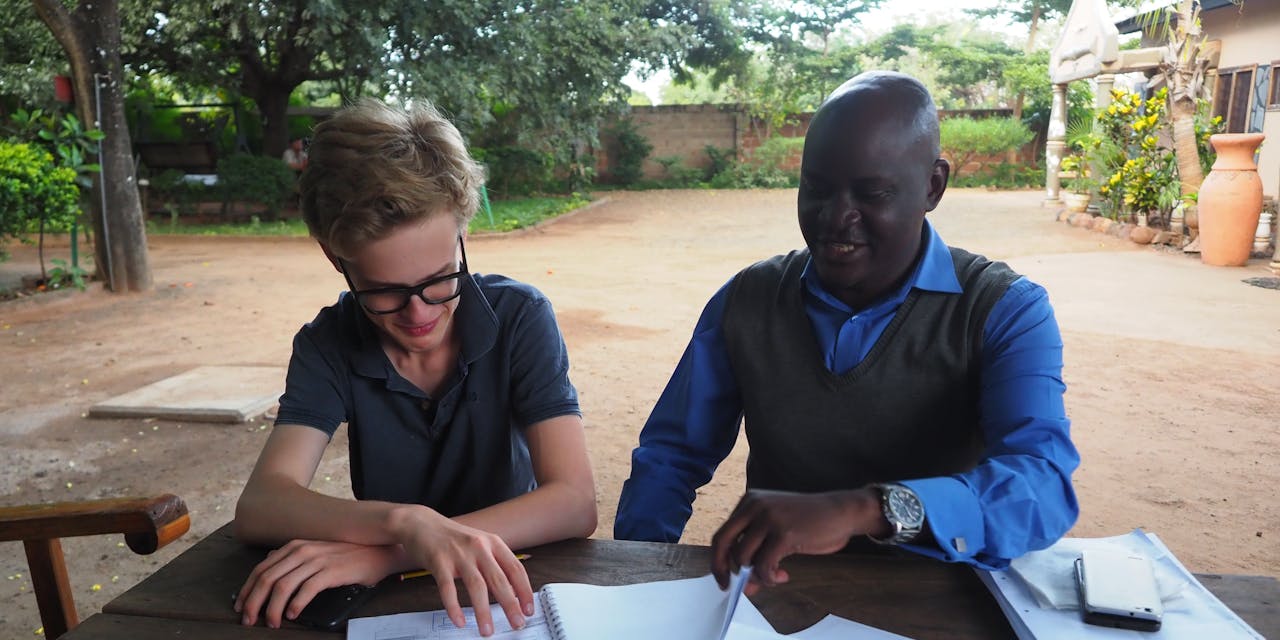Xavier en Kennedy bekijken bouwschetsen in Zambia.