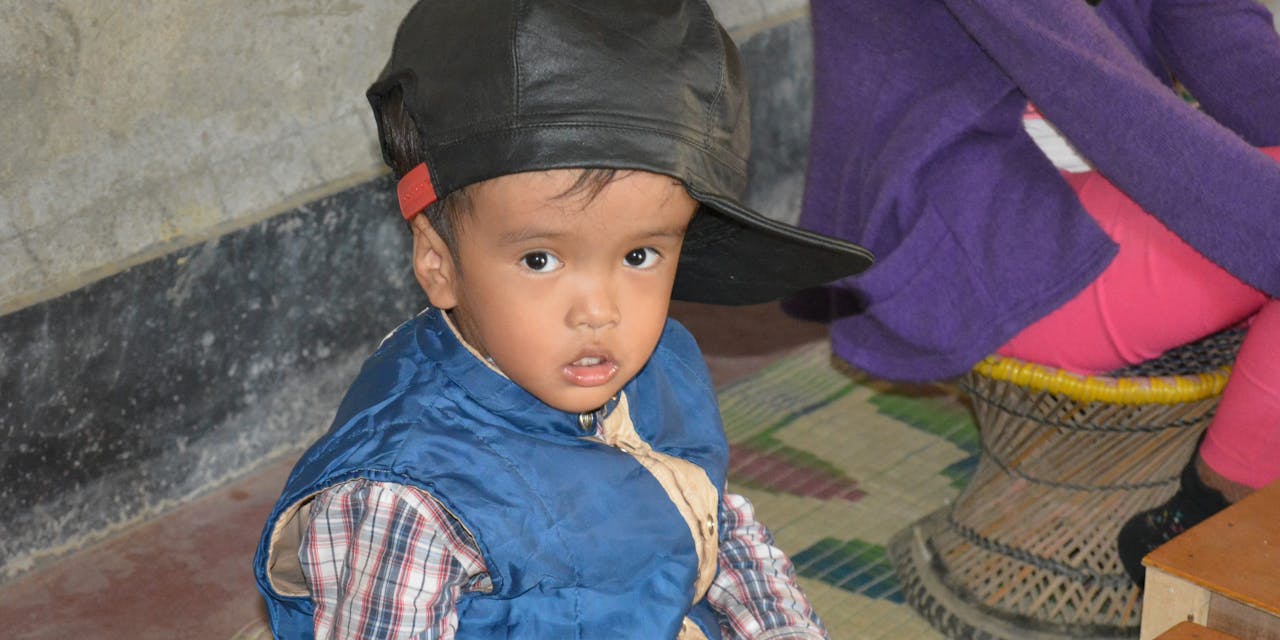 Een jongetje met een beperking kijkt in de camera in India.