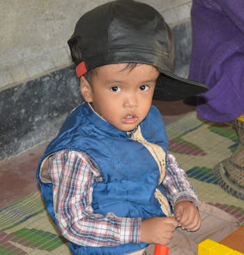 Een jongetje met een beperking kijkt in de camera in India.