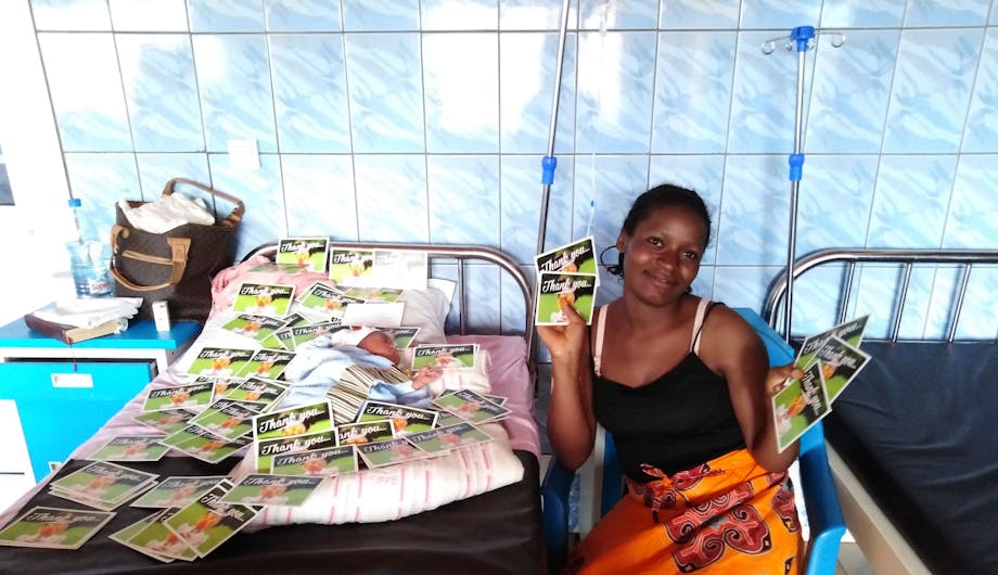 Een moeder in Kameroen poseert met bedankkaarten van Wilde Ganzen.