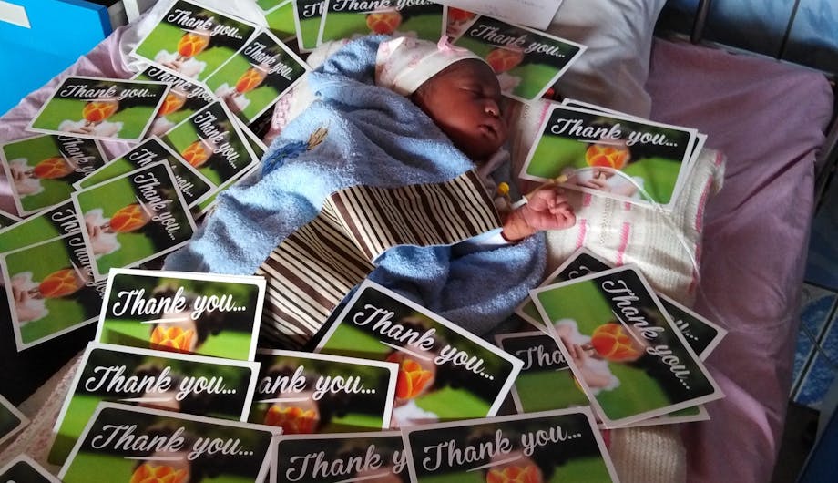 Een baby in Kameroen omringt door kaarten.