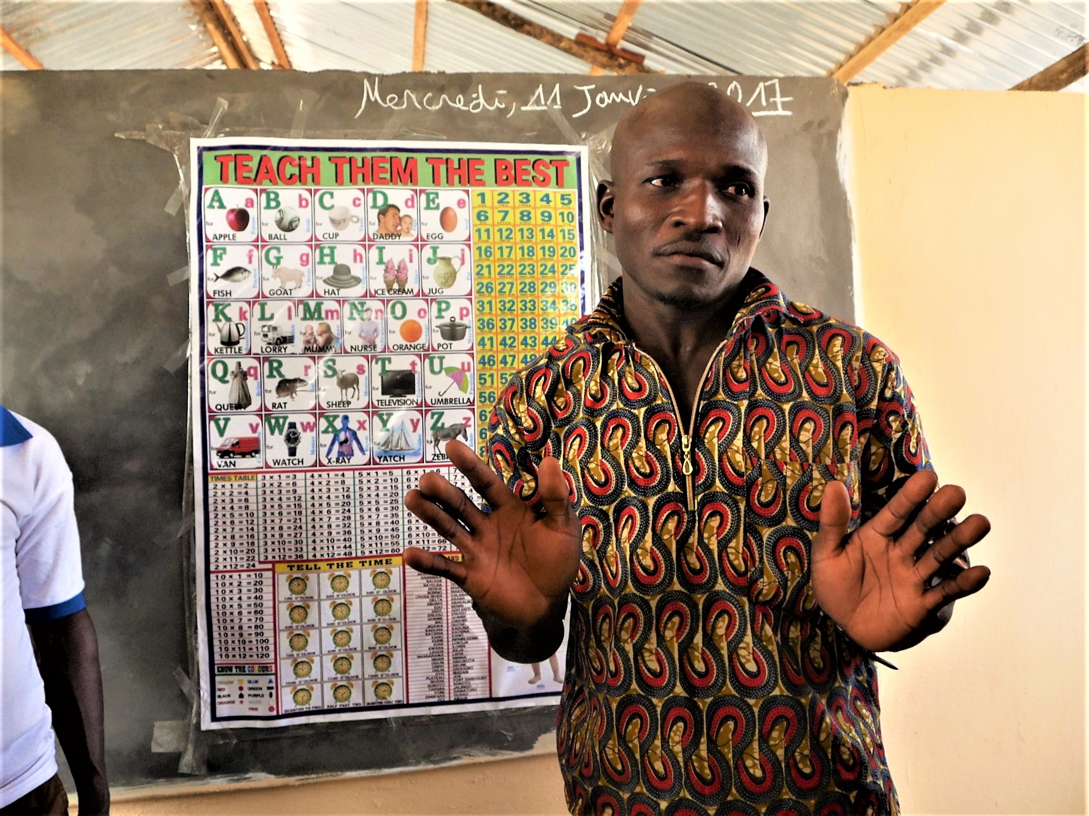 Een schoolmeester staat voor het bord in een klaslokaal in Togo.