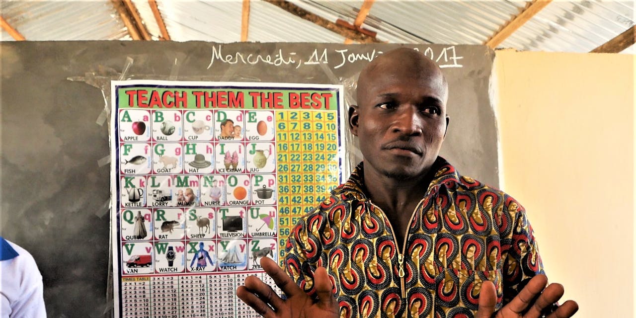 Een schoolmeester staat voor het bord in een klaslokaal in Togo.