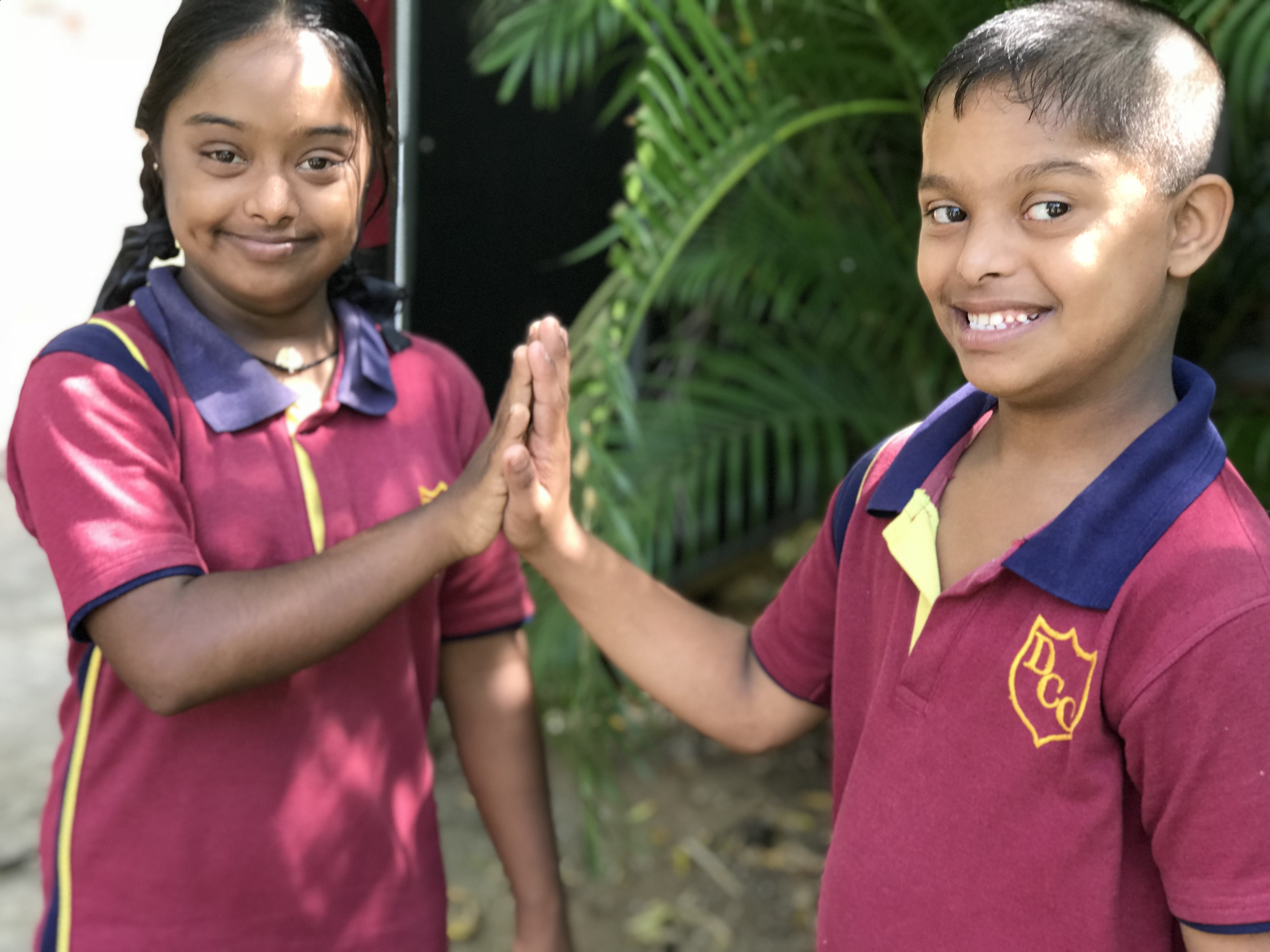 Een jongen en meisje met een beperking geven elkaar een highfive in Sri Lanka.