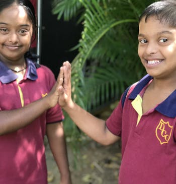 Een jongen en meisje met een beperking geven elkaar een highfive in Sri Lanka.
