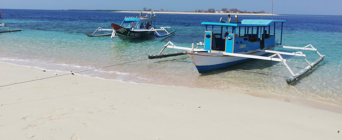 Twee boten liggen te wachten op een wit zandstrand in Lombok, Indonesië.