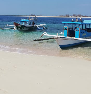 Twee boten liggen te wachten op een wit zandstrand in Lombok, Indonesië.
