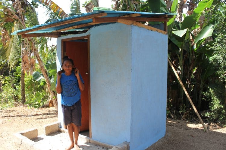 Een meisje poseert voor een nieuw gebouwde wc in Indonesië.