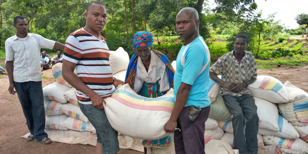 Twee mannen tillen een zak met mais.