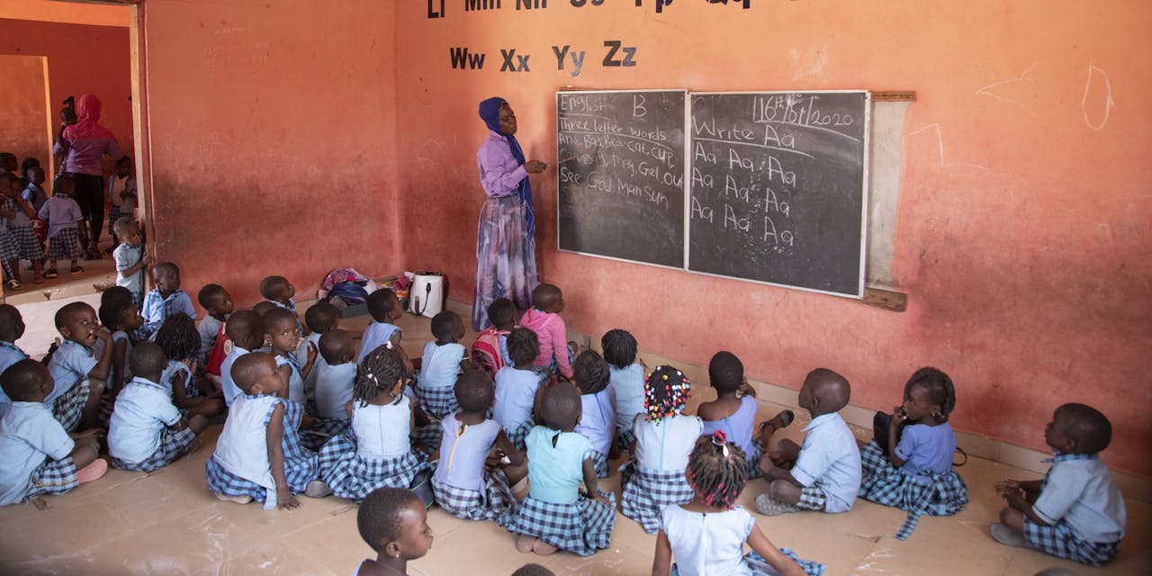 Kinderen zitten op de grond in de klas op een school in Ghana.