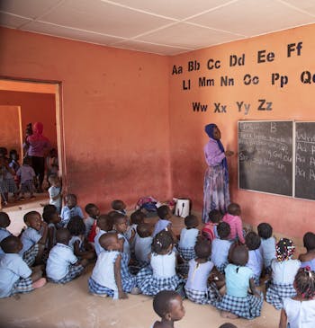 Kinderen zitten op de grond in de klas op een school in Ghana.