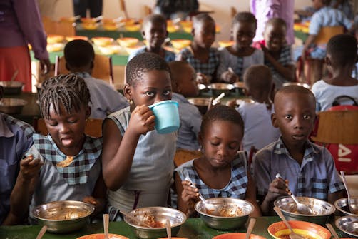 4 schoolkinderen krijgen een gezonde maaltijd in Ghana