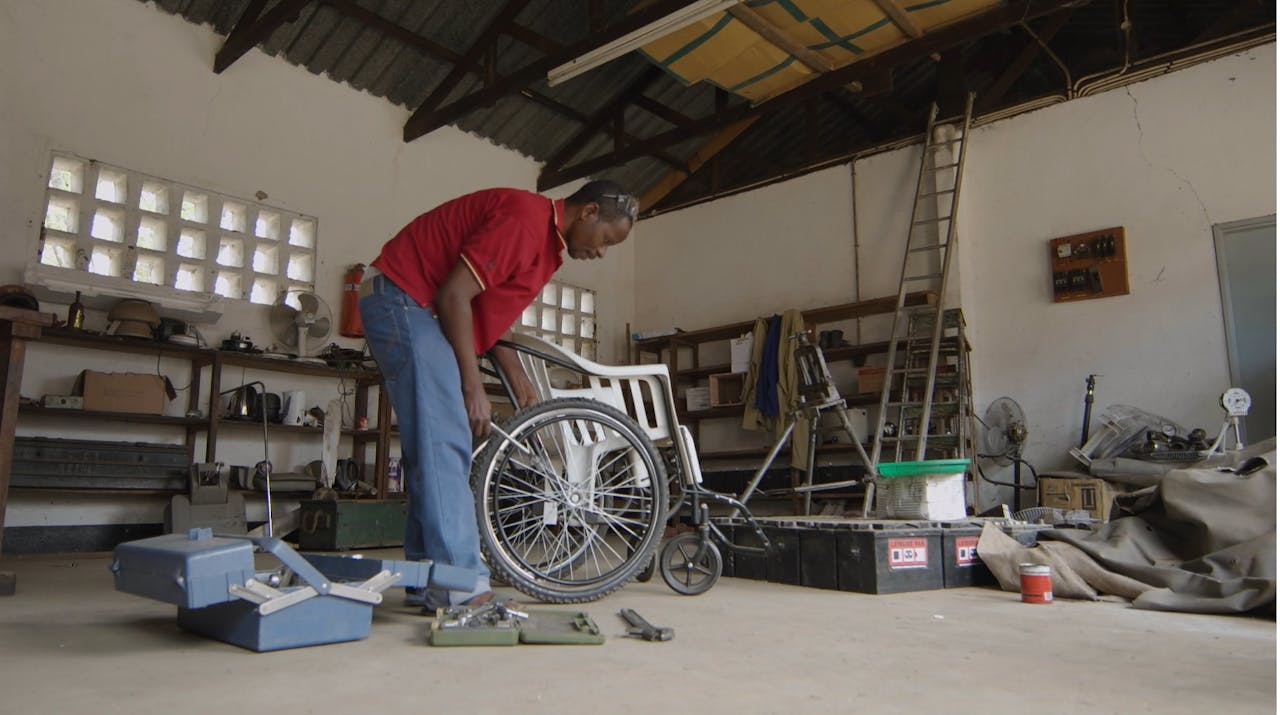 Een man repareert een rolstoel.