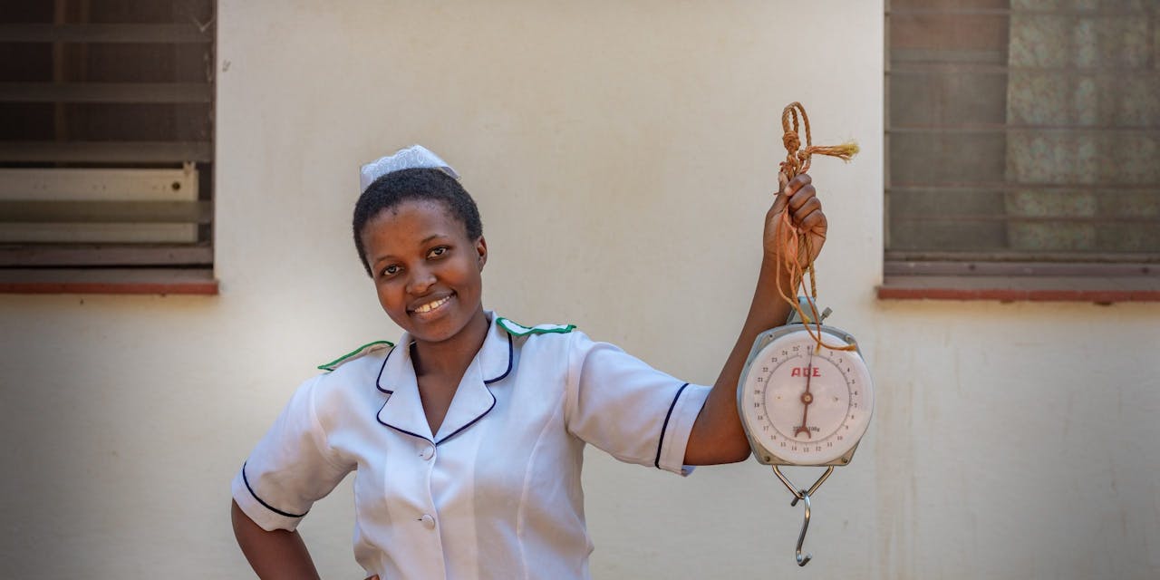 Verpleegster Akuzike Chimwaza laat een draagbare weegschaal zien in Malawi.