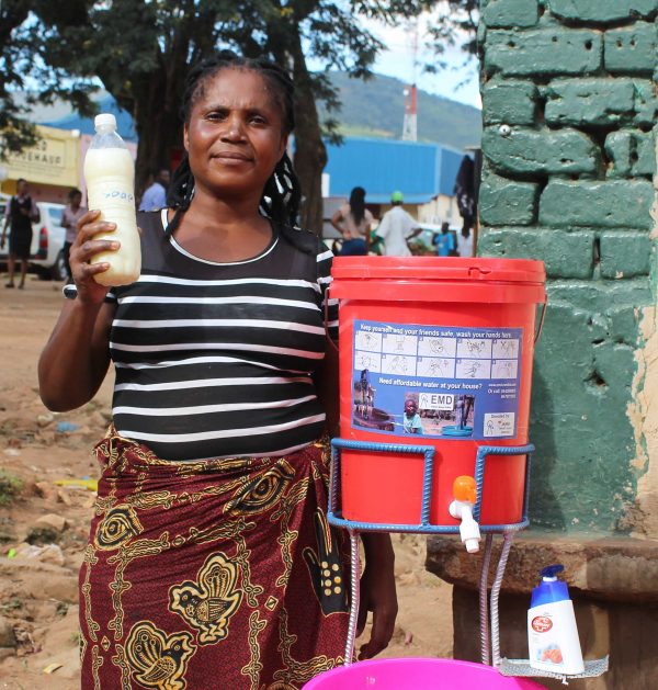 Een vrouw in Zambia met een fles vloeibare handzeep.