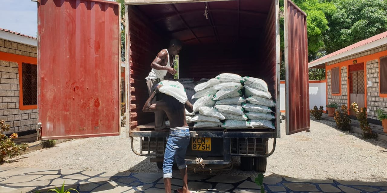 Zaken met zaden worden door twee mannen uit een vrachtwagen geladen in Kenia.