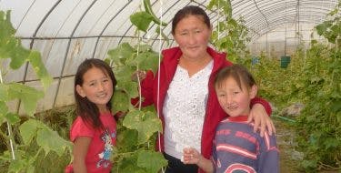 Een vrouw met twee kinderen in een groentekas in Mongolië.