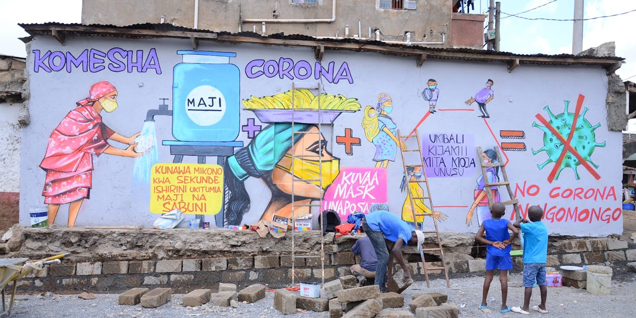 Twee kinderen kijken naar een muurschildering die waarschuwt tegen corona. Een jongerencentrum is hard nodig in de strijd tegen werkloosheid.