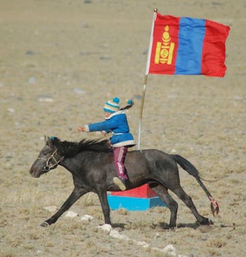 Tyleck rijd op een paard met een vlag in zijn hand.