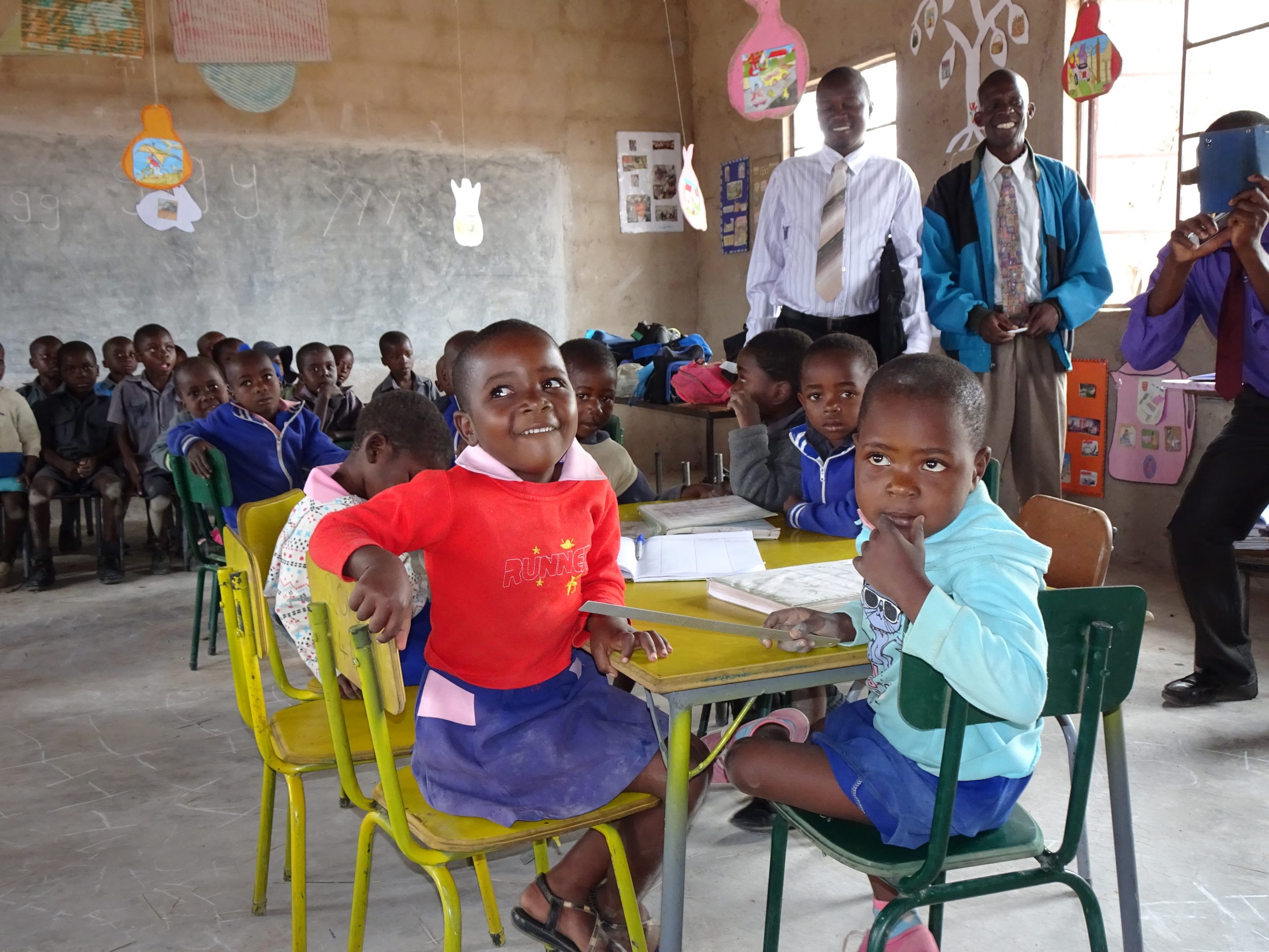 Twee kinderen op stoeltjes in de klas in Zimbabwe.