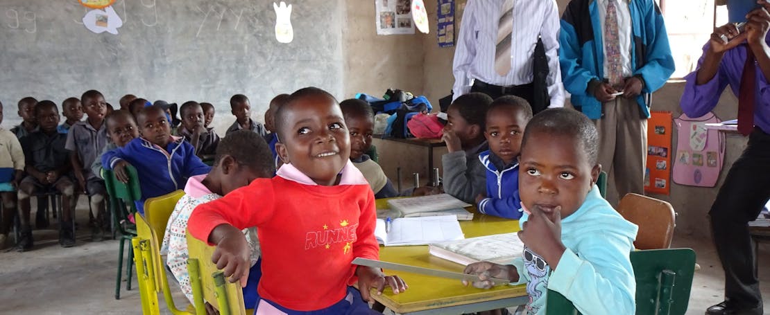 Twee kinderen op stoeltjes in de klas in Zimbabwe.