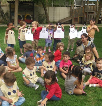 Een groep kleine kinderen zit op een grasveld, buiten hun school in Libanon.