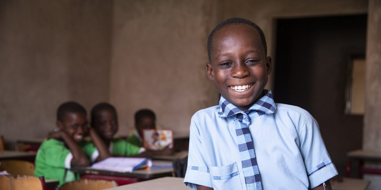 Een jongetje poseert lachend in zijn klas.