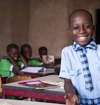 Een jongetje poseert lachend in zijn klas.