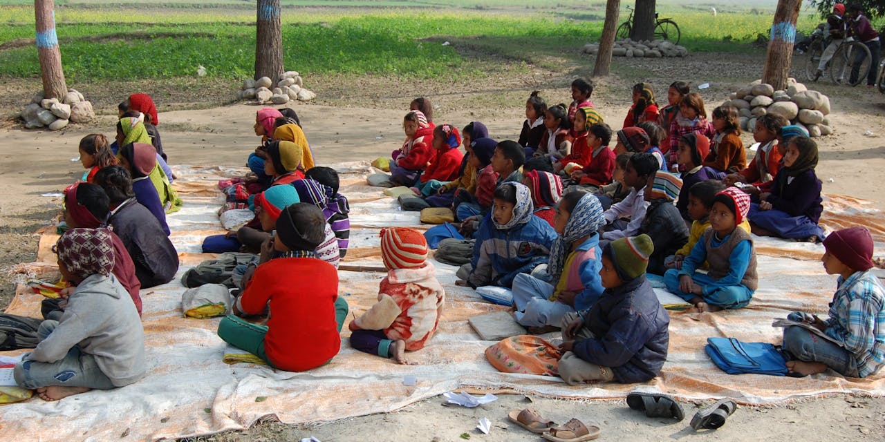 Een groep kinderen krijgt noodgedwongen buiten les in Nepal.