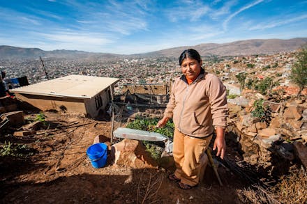 Een vrouw in haar tuintje met uitzicht over de stad in Bolivia.