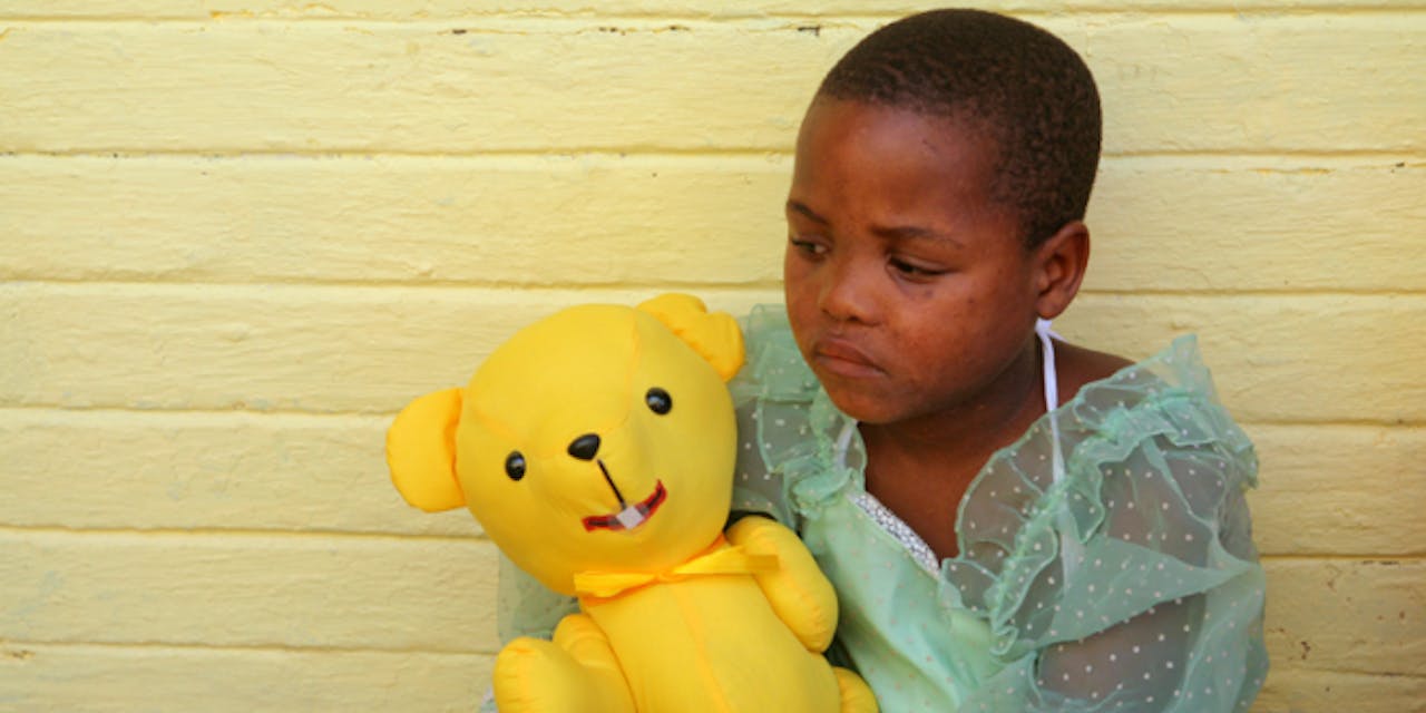 Een meisje in Zuid Afrika met een teddybeer van Bobby Bear.