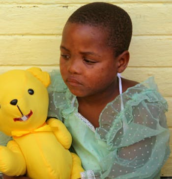 Een meisje in Zuid Afrika met een teddybeer van Bobby Bear.