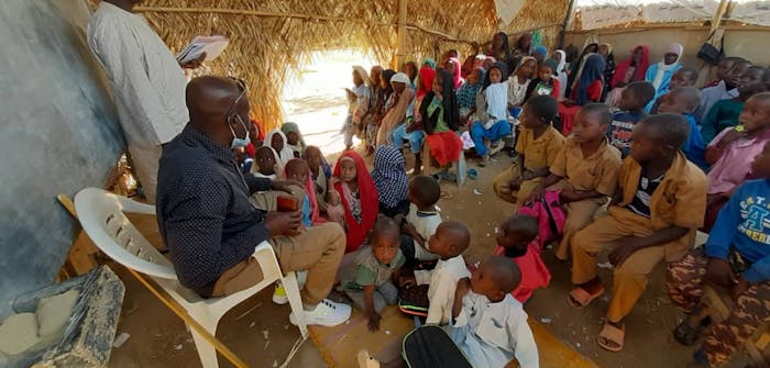 Een groep kinderen krijgt les in een tent in Tsjaad.