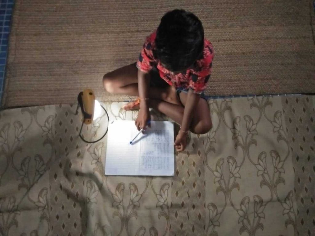 Een jongetje maakt zijn huiswerk bij een lamp in India.