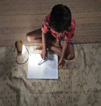 Een jongetje maakt zijn huiswerk bij een lamp in India.