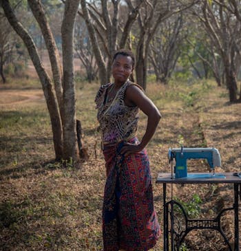 Een vrouw poseert naast een naaimachine in Malawi.