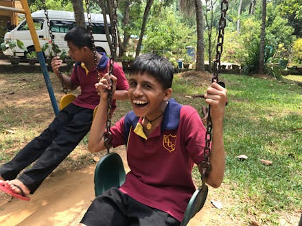 Een jongen met een beperking zit op een schommel in Sri Lanka