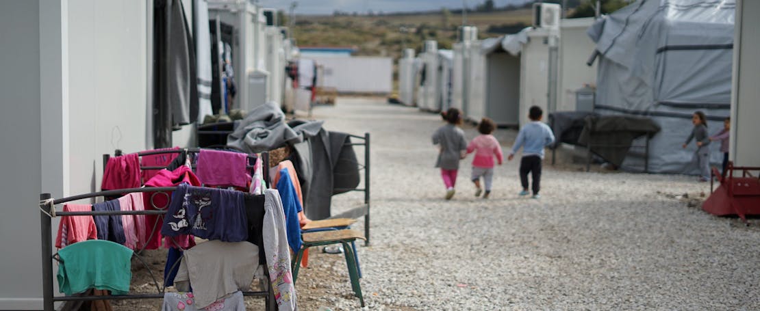 Drie kinderen lopen in een vluchtelingenkamp.